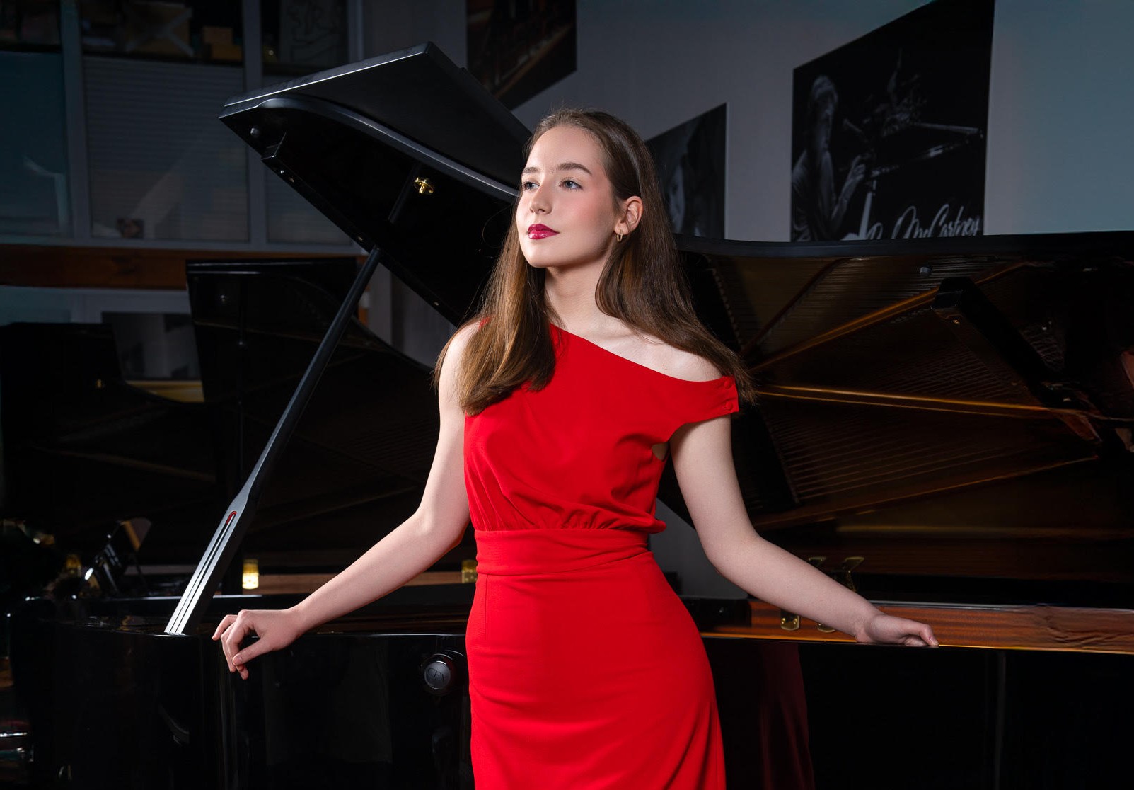 Zdjęcie przedstawia kobietę w czerwonej sukni na tle fortepianu